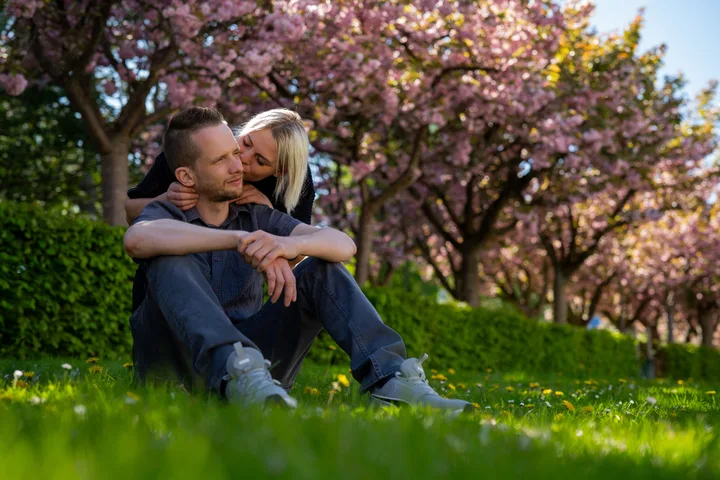 Par i omfavnelse under blomstrende kirsebærtræer